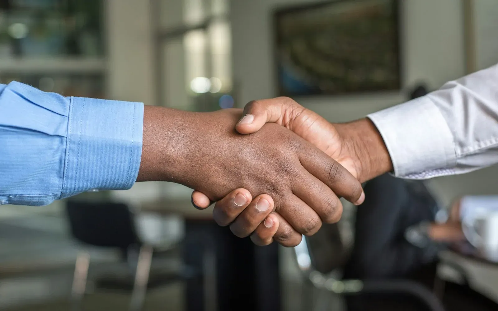 Two people shaking hands over a signed software contract